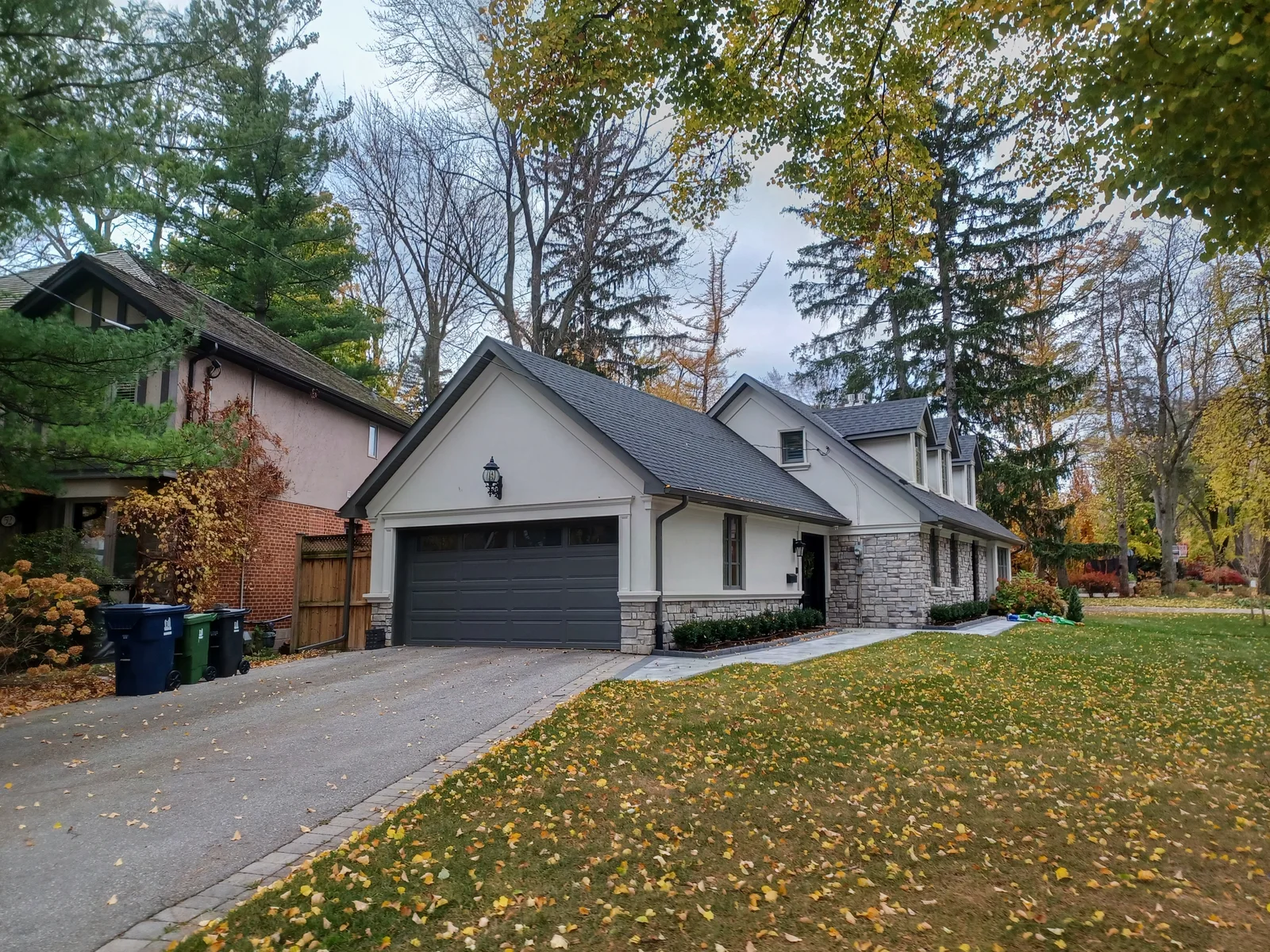 Detached home with a dark shingle roof surrounded by autumn trees